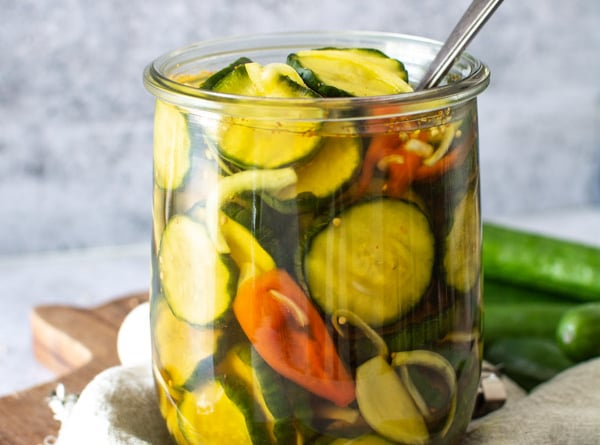 Large jar of spicy sweet bread and butter pickles with habanero peppers and onions.