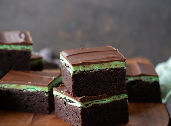 Two stacked chocolate mint brownies on a wooden cutting board