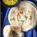 Flakey Paratha flat bread stacked on a cloth with a bowl of lentils