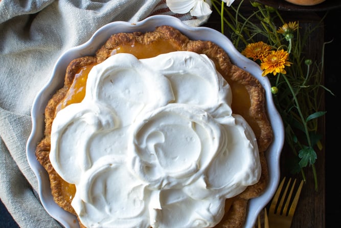Fresh peach pie topped with whipped cream.
