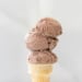 Three scoops of ice cream stacked on a cone.