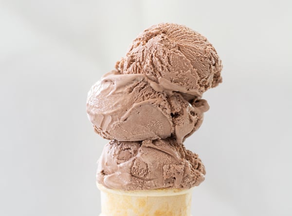 Three scoops of ice cream stacked on a cone.